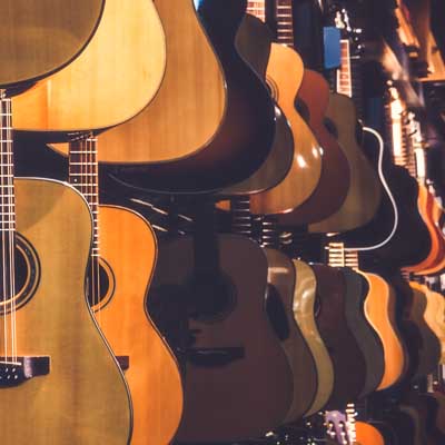 Guitars hanging up in a row in a shop. Representing guitar lessons at SFE Music School