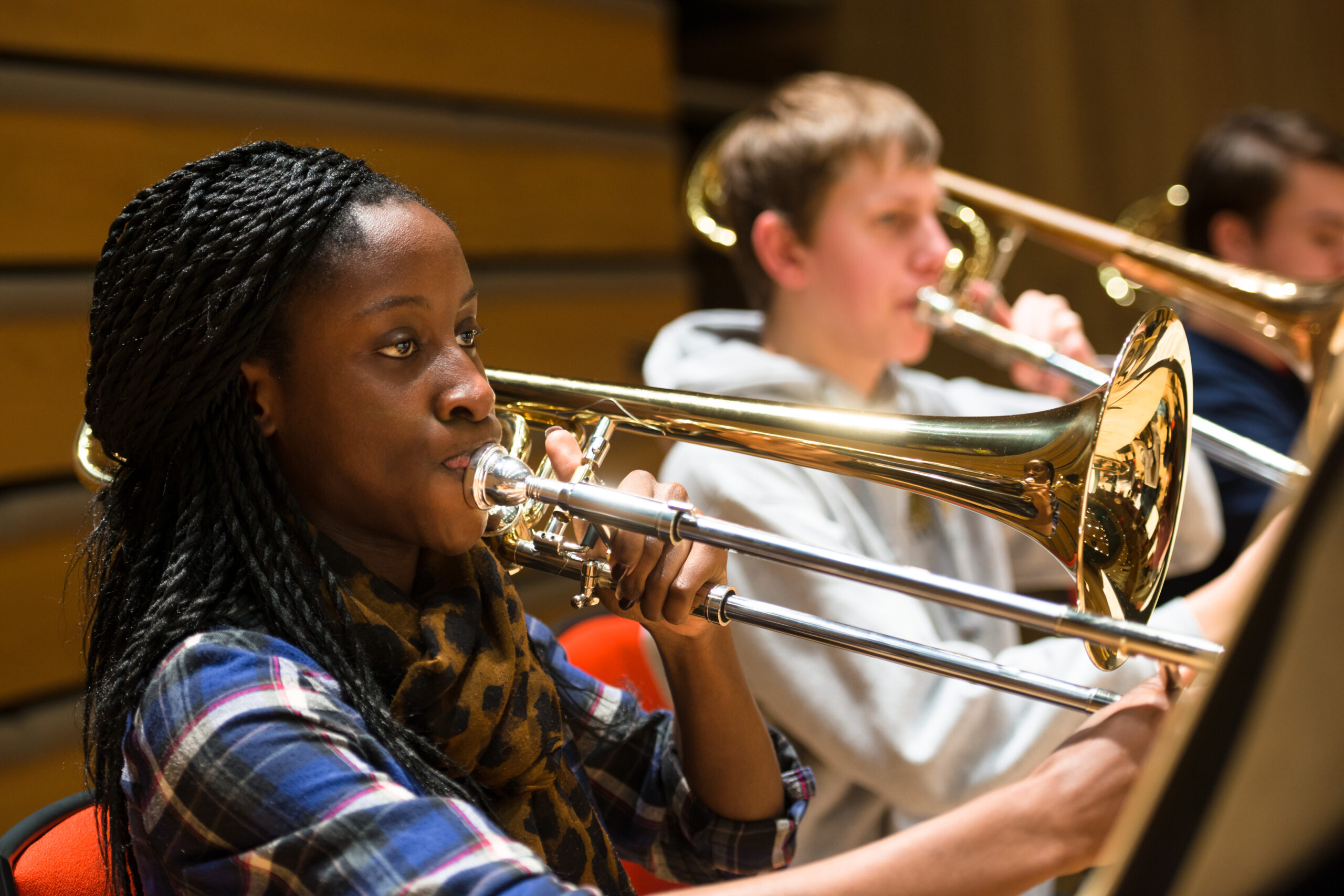 Girl playing trumpet with other trumpet players in the background. Representing wind and brass instrument lessons at SFE Music school